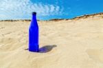 Blue Water Bottle In Dry Yellow Sand Stock Photo