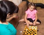 Little Girl Playing Draughts With Her Mother Stock Photo
