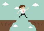 Business Concept, Businessman Jump Through The Gap To Another Cliff Stock Photo