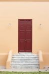Wooden Brown Door On Orange Wall Stock Photo