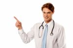 Smiling Male Physician Pointing Away Stock Photo
