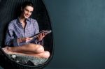 Smiling Woman On Bubble Chair Reading Magazine Stock Photo