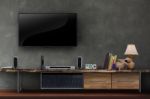 Tv On Concrete Wall With Wooden Media Furniture Stock Photo