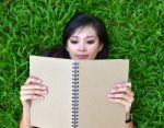 Woman Lying On Grass With  Book Stock Photo