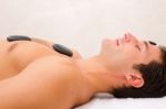 Young Man Enjoying A Hot Stone Massage Stock Photo