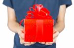 Man Holding Red Christmas Gift In Front Of Body Stock Photo