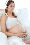 Pregnant Woman Sitting On Sofa At Home And Listening Music In He Stock Photo