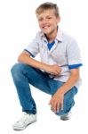 Smiling Young Boy Squatting Down Stock Photo