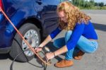 Woman Checking Air Pressure Of Car Tire Stock Photo