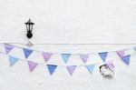 Colorful Party Flags Bunting Hanging On White Wall Background With Wall Lamp Light. Minimal Hipster Style Design Stock Photo