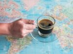 A Hand Holding A Cup Of Black Coffee On World Map Stock Photo
