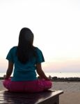 Woman Meditating On The Beach At Sunset Stock Photo