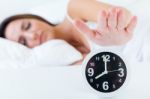 Beautiful Young Woman Turning Off The Alarm Clock Stock Photo