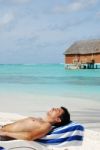 Young Man Sunbathing In A Maldivian Island Beach Stock Photo