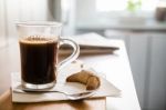 Black Coffee In Glass With Spoon And Croissant On Wooden Table Stock Photo