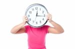 Shy Girl Hiding Her Face With Wall Clock Stock Photo