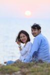 Portrait Of Asian Younger Man And Woman Relaxing Vacation At Sea Side Happiness Emotion Against Sun Set Sky Background Stock Photo