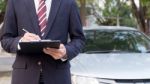 Close-up Of A Man Standing In Front Of Car Holding Clipboard In Stock Photo