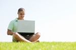 A Young Men Sit On The In The Park Using A Laptop Stock Photo