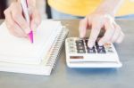 Hand Holding Pen And Pressing Calculator Buttons Stock Photo