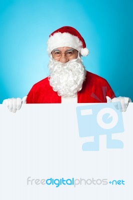 Aged Santa Standing Behind A Blank Ad Board Stock Photo