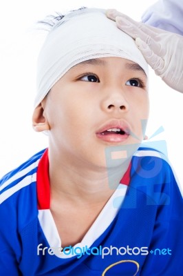 Asian Boy In Blue Sportswear With Trauma Of The Head. Doctor Makes A Bandage On Head Patient Stock Photo