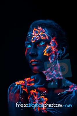 Beautiful Flowers In Uv Light On A Young Girl Face And Body Stock Photo