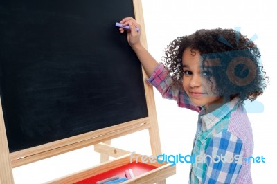 Beautiful Little Girl Writing On Classroom Board Stock Photo
