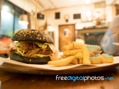 Black Burger With French Fries In Cafe Stock Photo