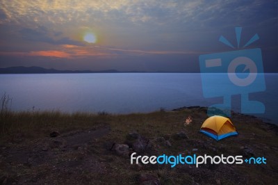 Camping Tent On Rock Mountain With Sun Rising On Dramatic Sky Stock Photo