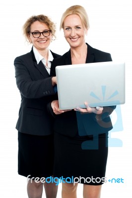 Cheerful Corporate Ladies Using Laptop Stock Photo