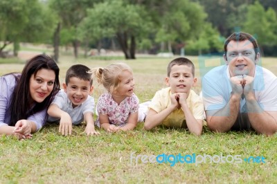 Cheerful Family Of Five Lying On Lawn Stock Photo