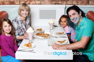 Cheerful Family Of Four Enjoying Dinner Stock Photo