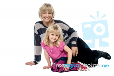 Cheerful Mum And Daughter Sitting On Studio Floor Stock Photo