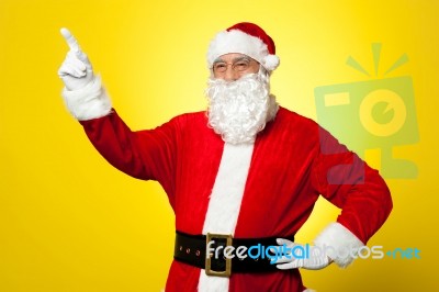 Cheerful Santa Pointing Away. Copy Space Concept Stock Photo