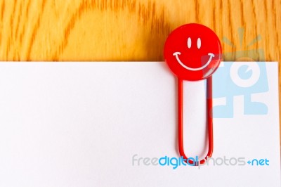 Close Up Of A  Red Paper Clip And White Paper On Wood Table Stock Photo