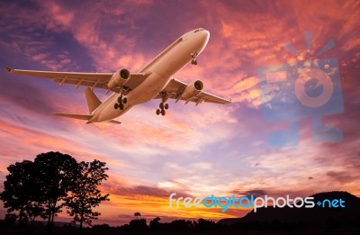 Commercial Airplane Flying At Sunset Stock Photo