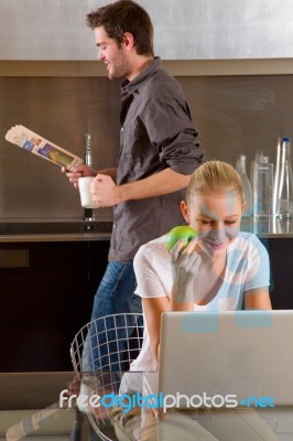 Couple At Kitchen Using Laptop Stock Photo