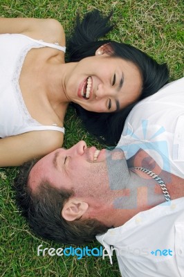 Couple Lying On Lawn Stock Photo