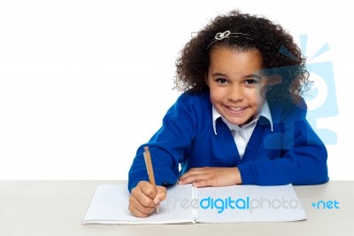Cute Primary Kid Writing Her Assignment Stock Photo
