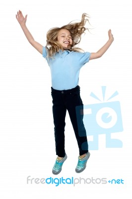Delighted Young Girl Jumping High In The Air Stock Photo