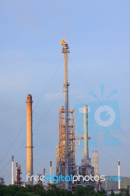 Fire Burning Over Oil Refinery Chimney Against Blue Sky Stock Photo