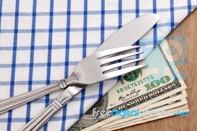 Fork And Knife On Dollar Bills Stock Photo