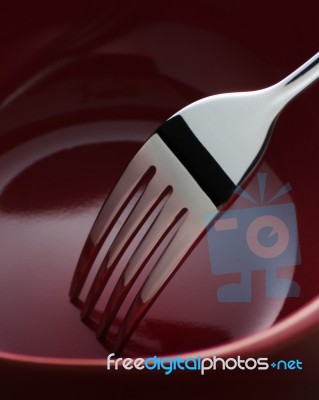 Fork In Dark Red Ceramic Dish Stock Photo