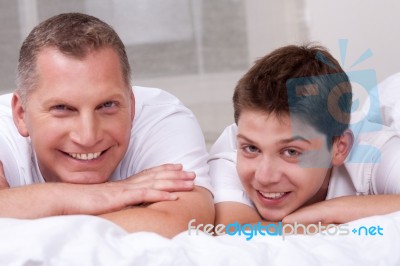 Friendly Father And Son Smiling And Lying On The Bed Stock Photo