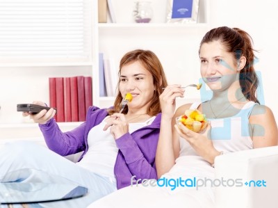 Girls Watching Tv And Eating Fruit Stock Photo