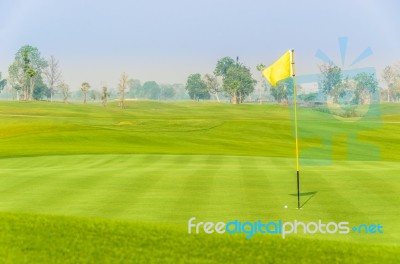 Golf Ball Near Hole On Green With Yellow Flag Stock Photo