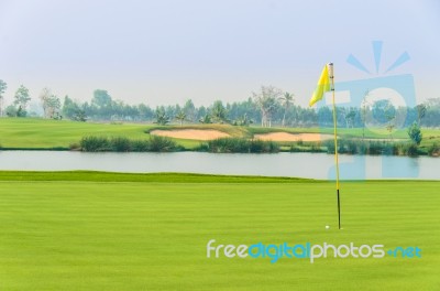 Golf Ball On Green Near Hole With Yellow Flag Stock Photo