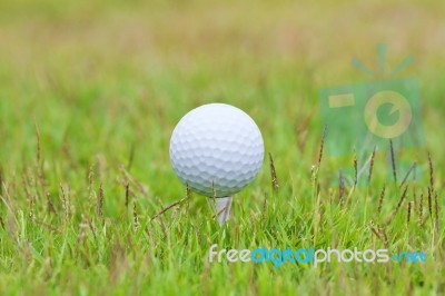 Golf Ball On Tee Over A Blurred Green Stock Photo