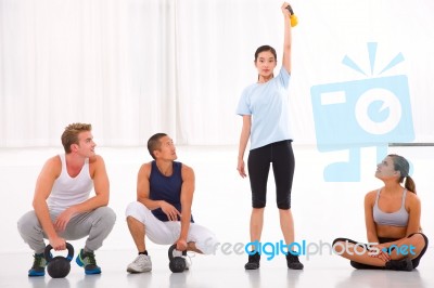 Group Of Diverse People Looking Woman Lifting Kettlebell In Gym Stock Photo